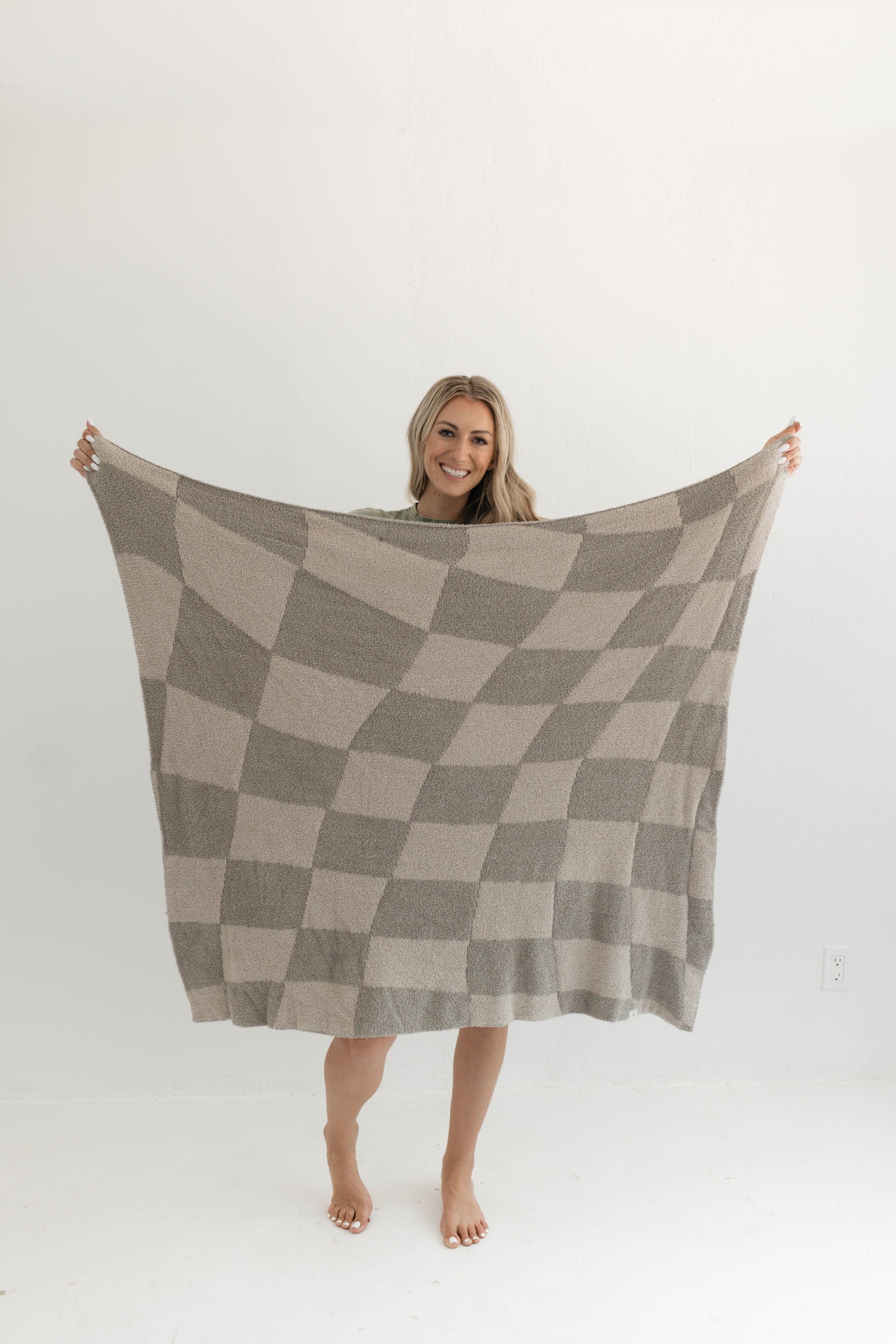 Oversized wavy checkerboard plush throw blanket in warm neutral tones, perfect for cozy snuggles.